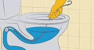 how to unblock toilet using hanger. An image of a person using a bent wire hanger to unclog toilet with hanger.