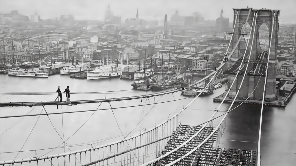 Historic image of the Brooklyn Bridge under construction, displaying the progression of its unique suspension/cable-stayed design, foundational piers, and intricate web of cables, a testament to 19th-century engineering prowess